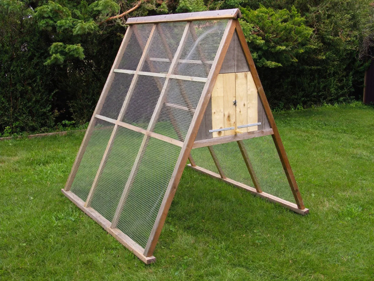 A-frame chicken coop on mown grass, mesh sides sloping from a ridge to the base rails