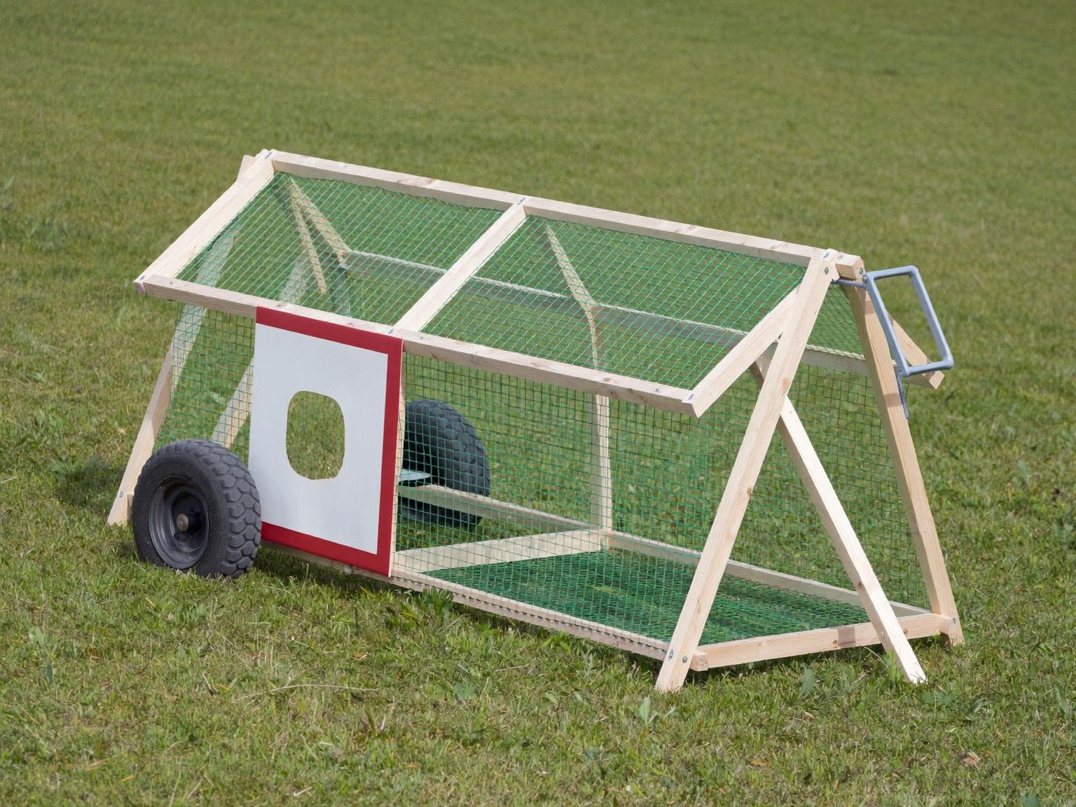 A-frame chicken tractor with mesh sides, two wheels and a lifting handle on grass