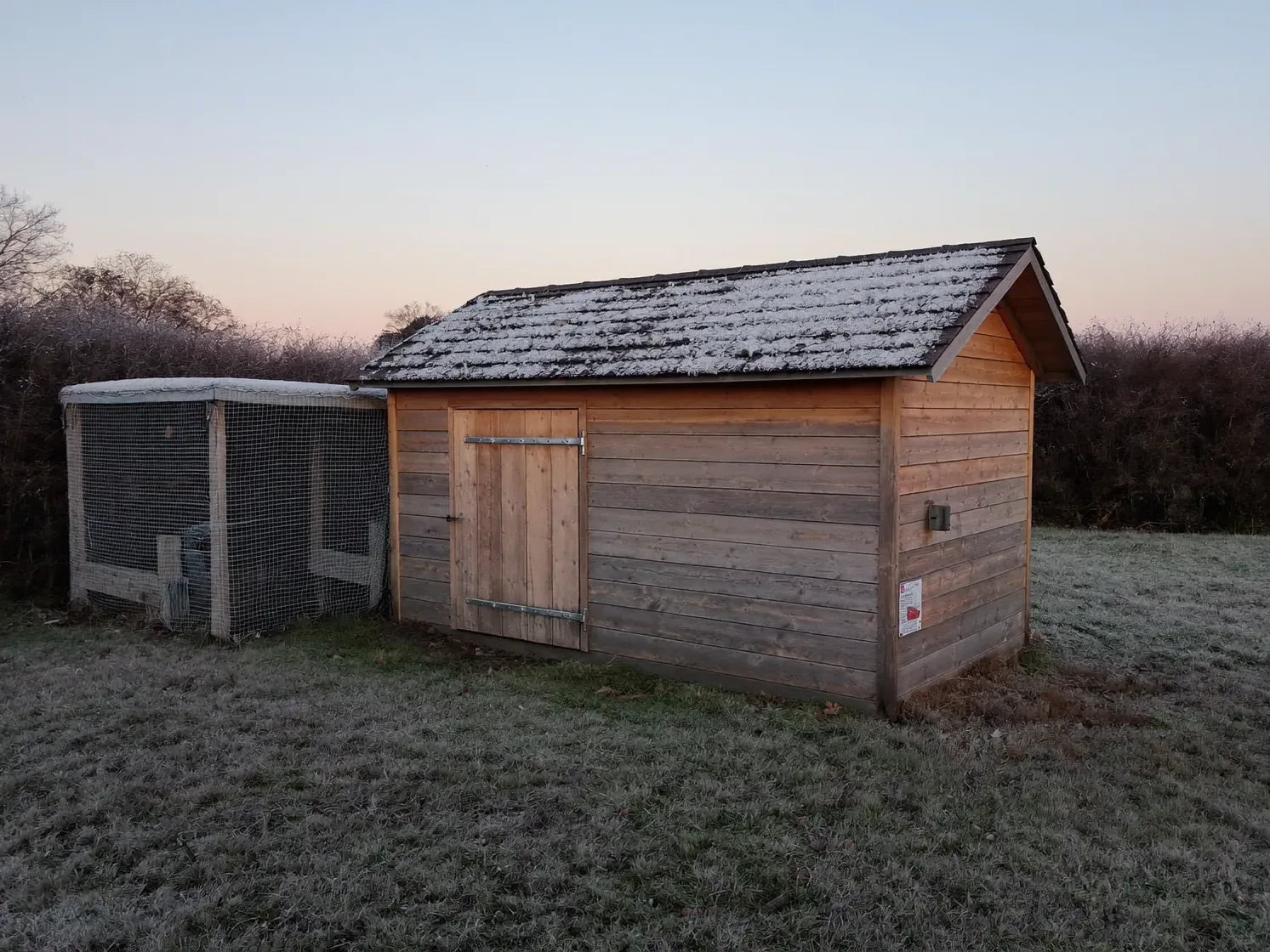 Frost on the grass around a closed-up wooden hen house and its run at first light